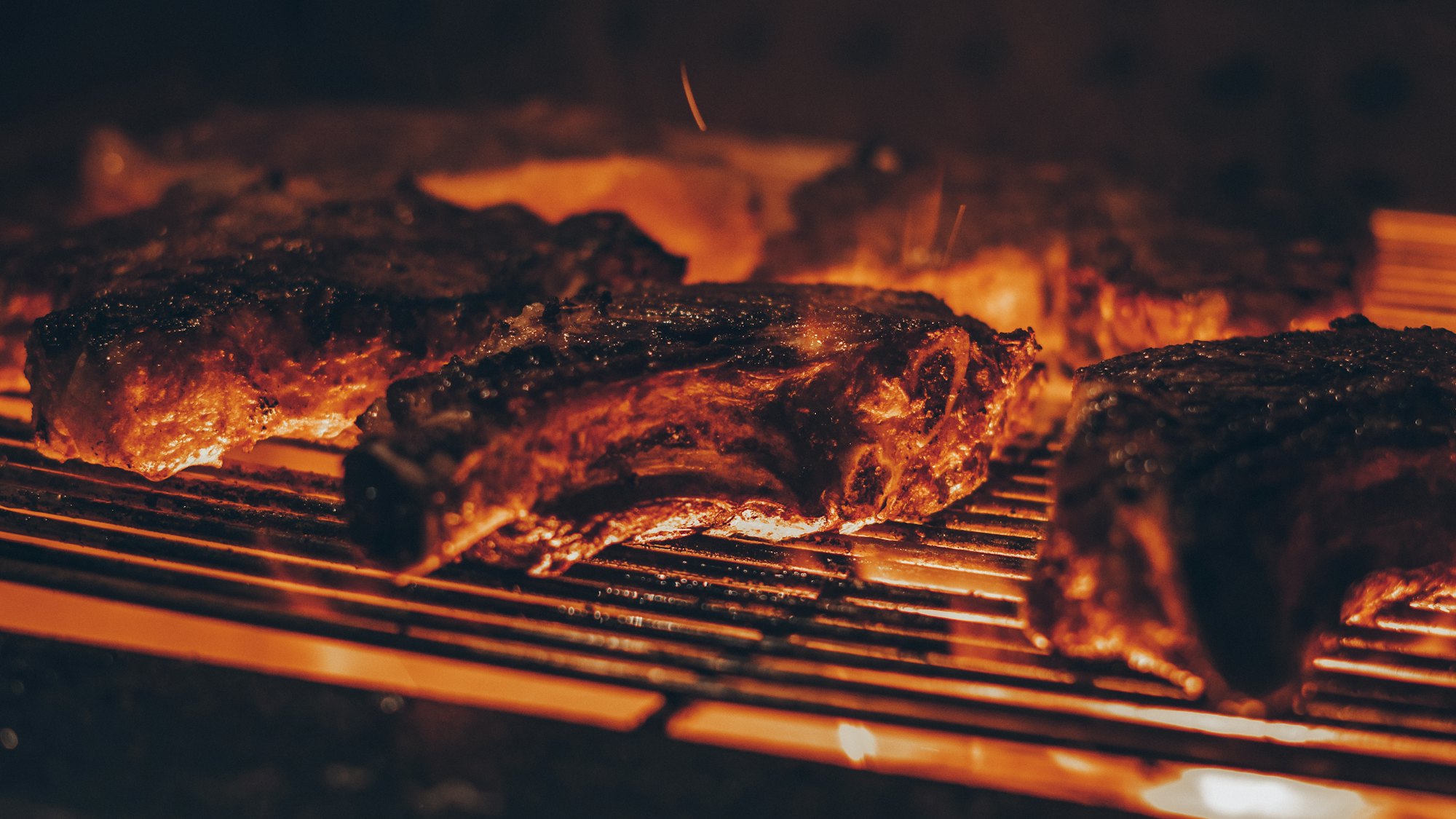 Costillas dorándose sobre la parrilla con llamas